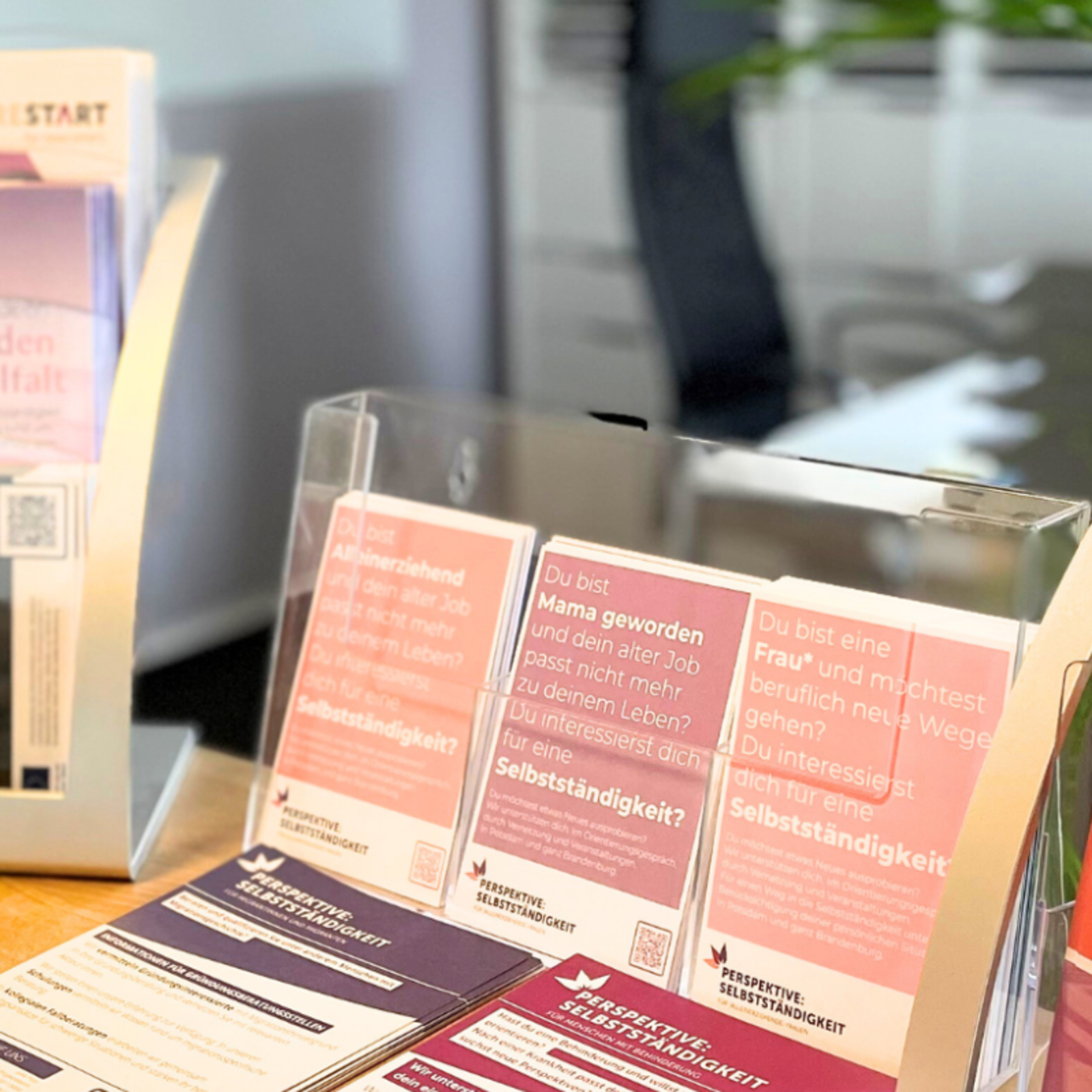 Informationsbroschüren und Flyer in Haltern auf einem Tisch im Standort Potsdam, Schiffbauergasse, mit Titeln wie 'MIT EINANDER' sichtbar